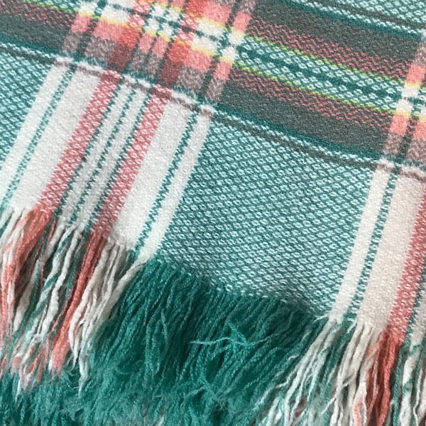 Image of close up of fringed pink and green blanket
